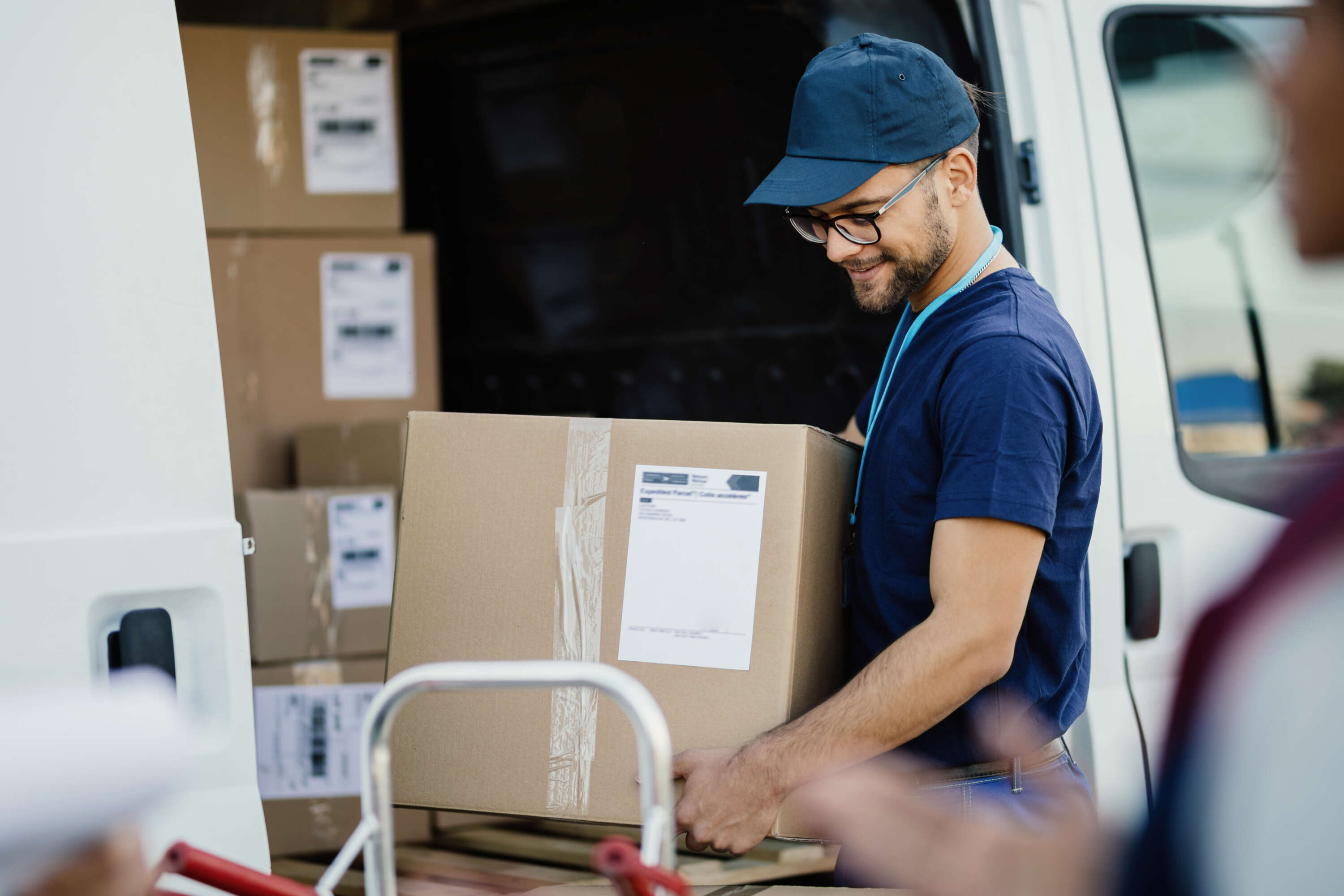 Courier driver lifting a parcel from a van while making deliveries